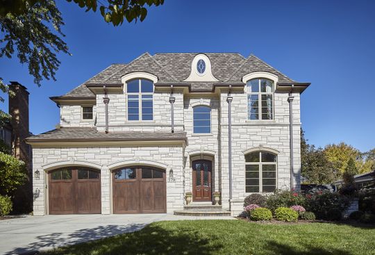 A large white brick house with a wooden garage door