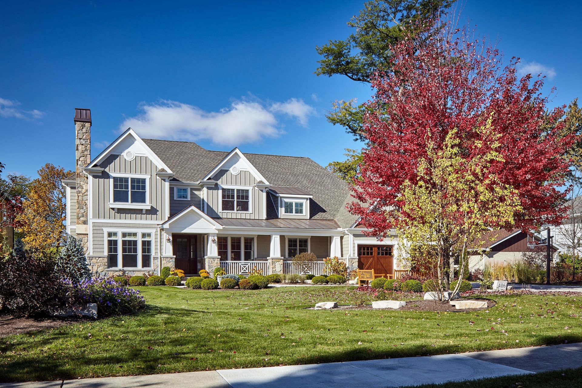 A large house with a large lawn and a tree in front of it.