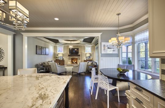 A kitchen with a marble counter top and a dining table and chairs