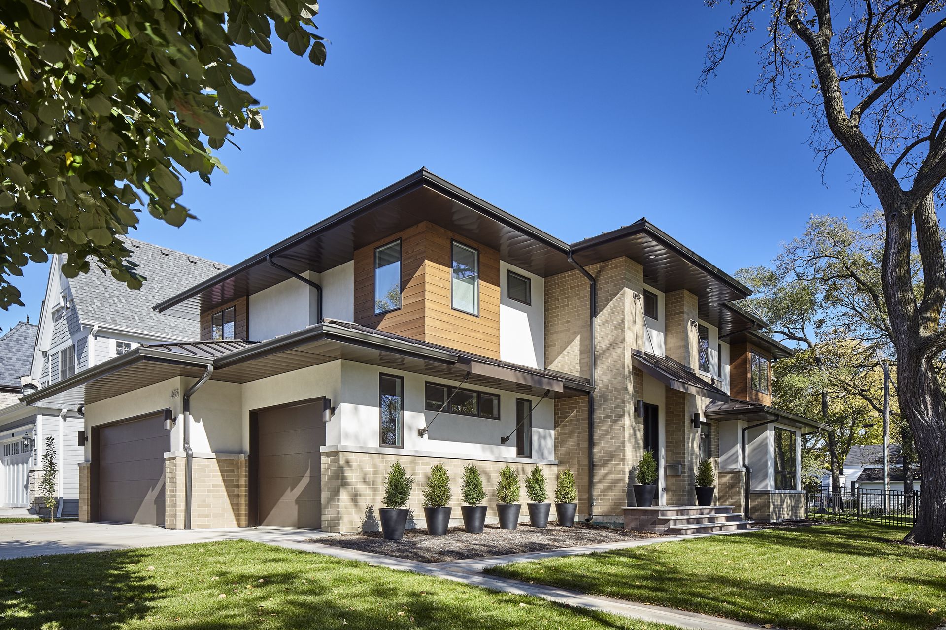 A large house with a lot of windows is sitting on top of a lush green lawn.