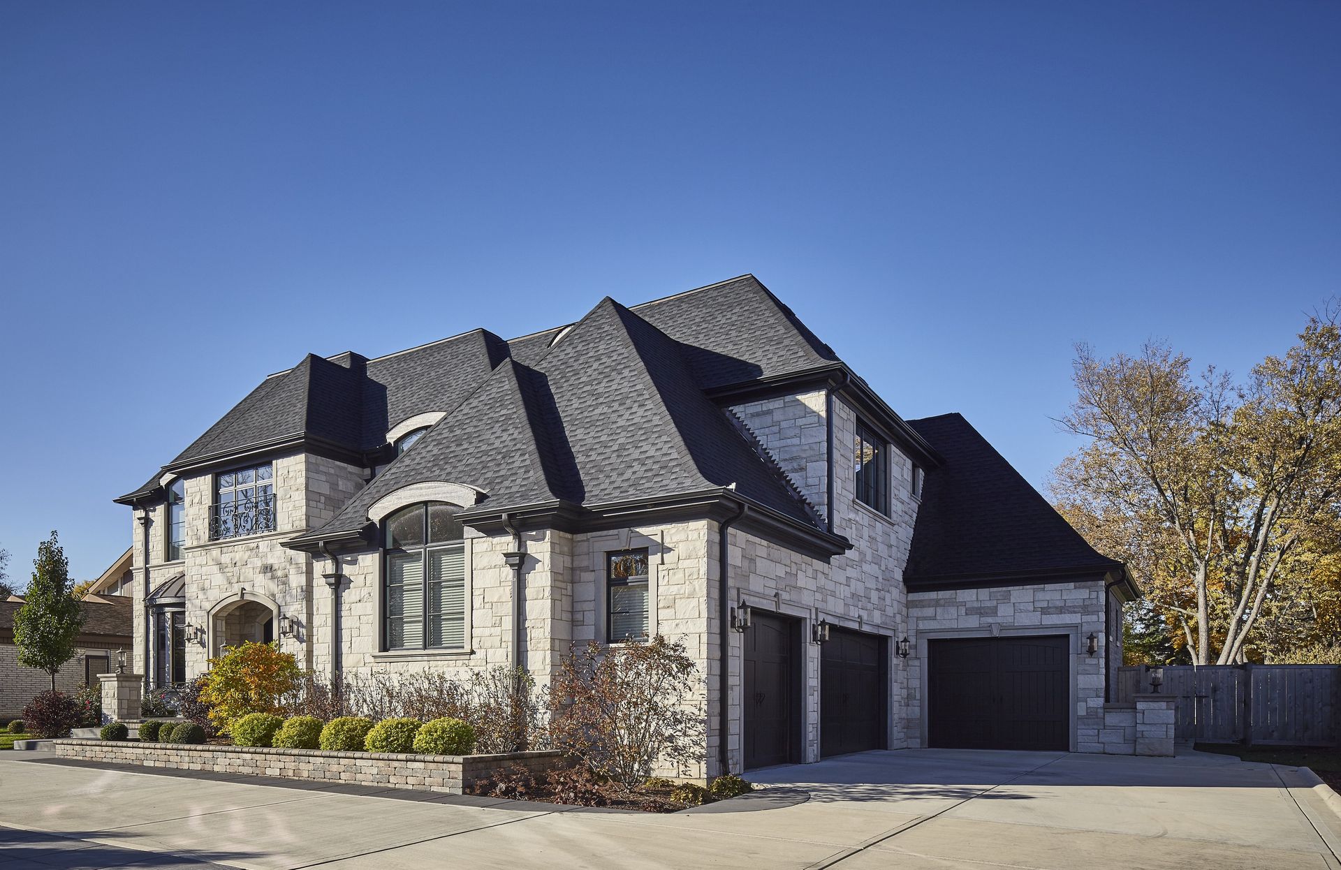 A large brick house with two garages and a blue sky in the background.