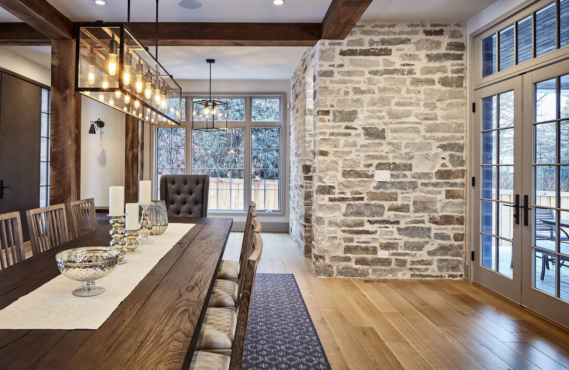 A dining room with a long wooden table and chairs and a brick wall.