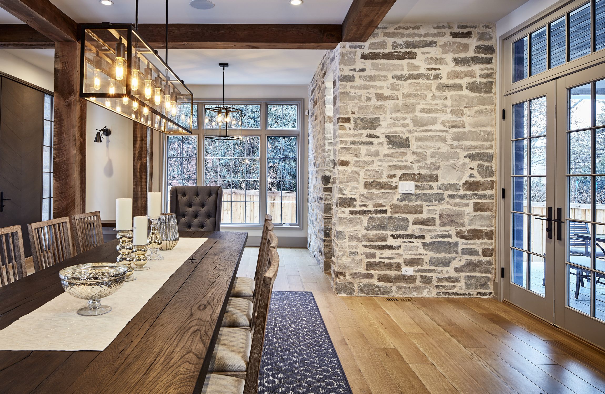A dining room with a long wooden table and chairs and a brick wall.