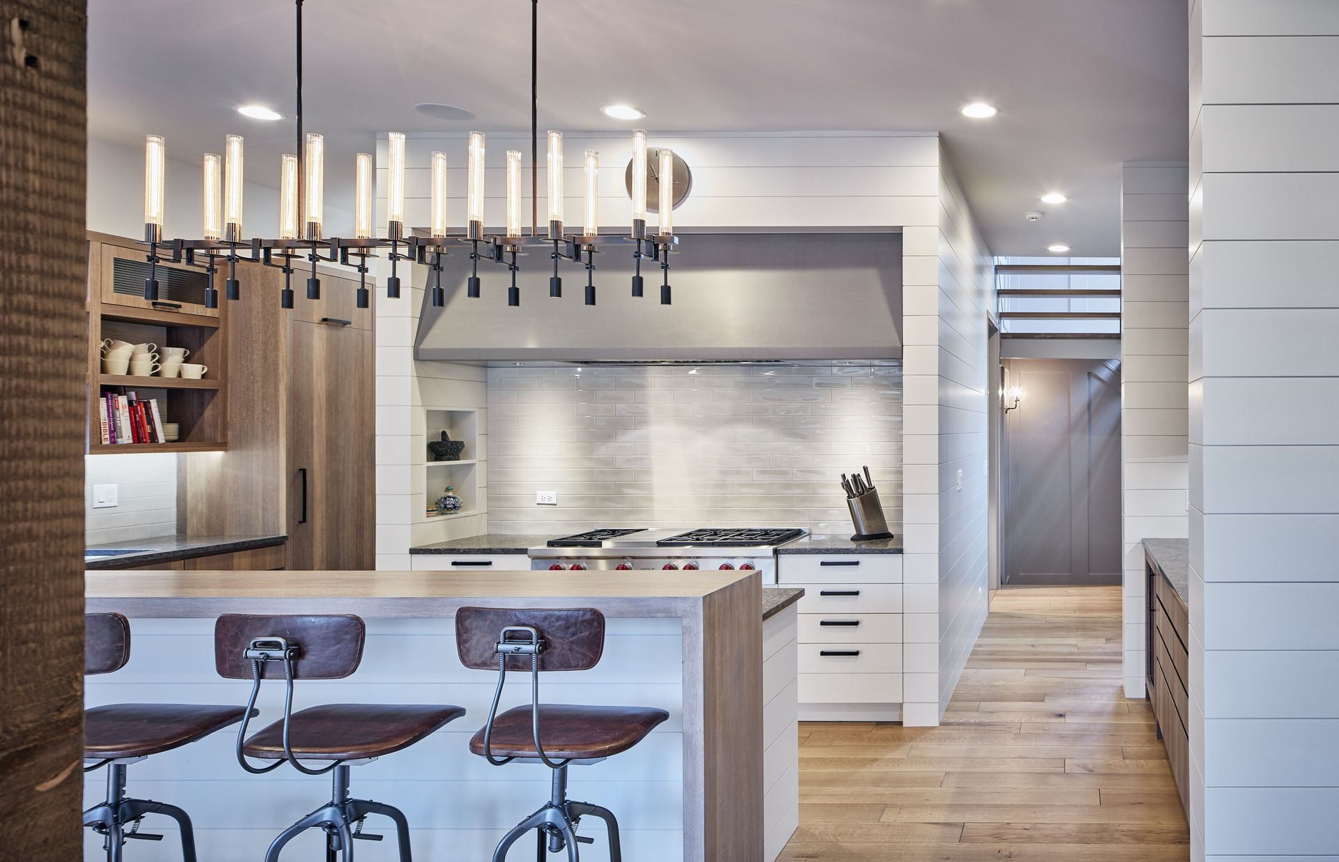 A kitchen with stools and a chandelier hanging from the ceiling