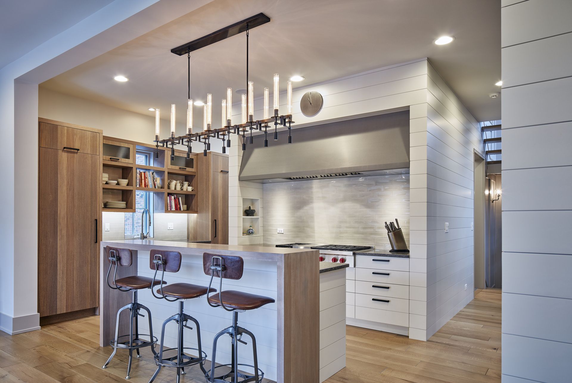 A kitchen with stools and a chandelier hanging from the ceiling