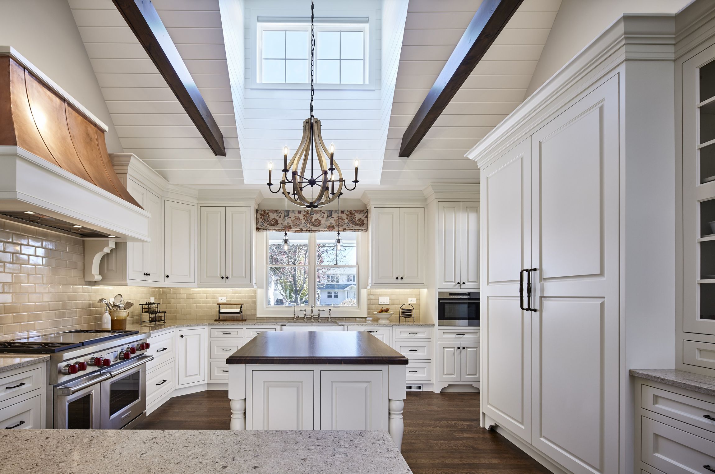 A kitchen with white cabinets , granite counter tops , stainless steel appliances and a large island.