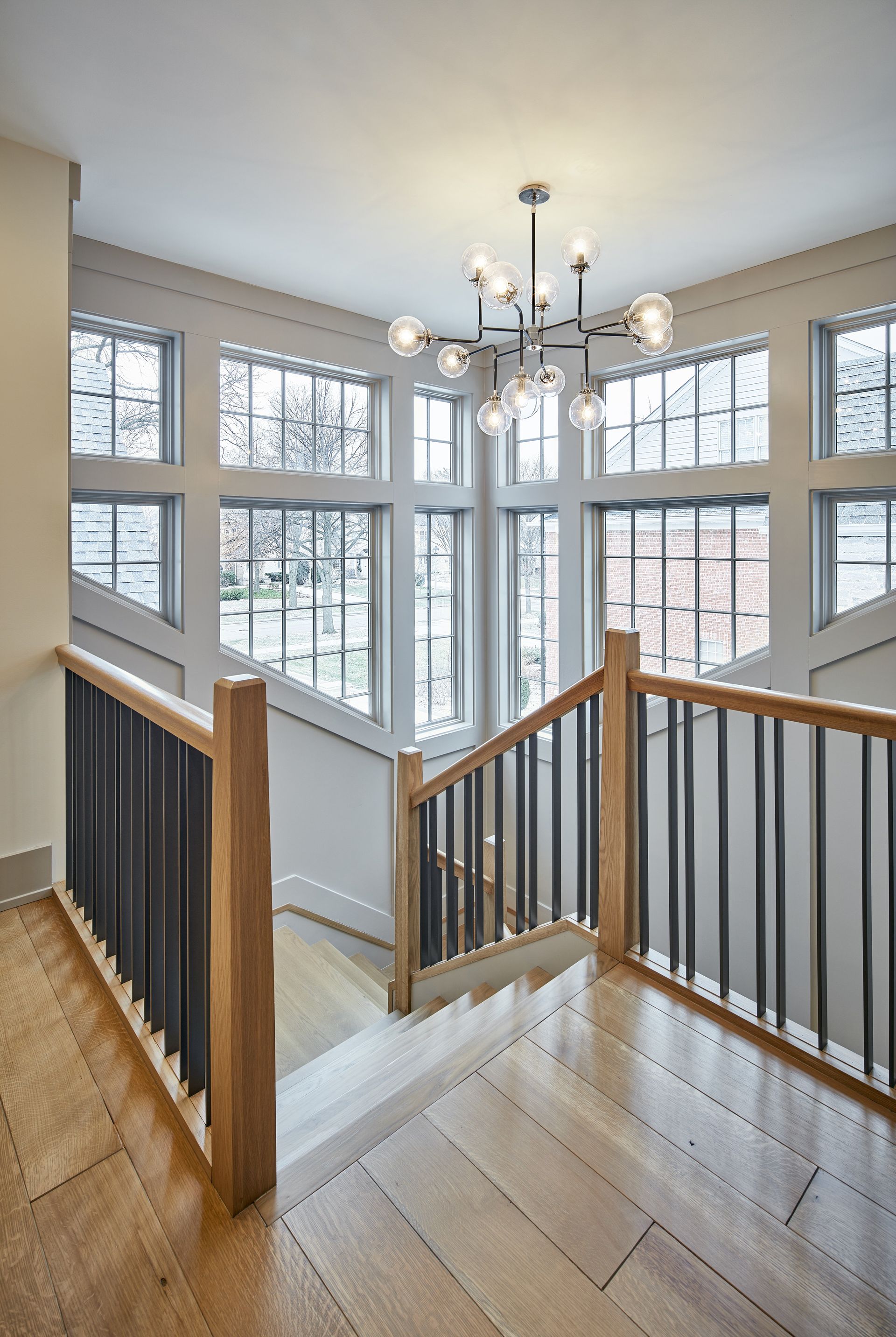 A staircase in a house with lots of windows and a chandelier.