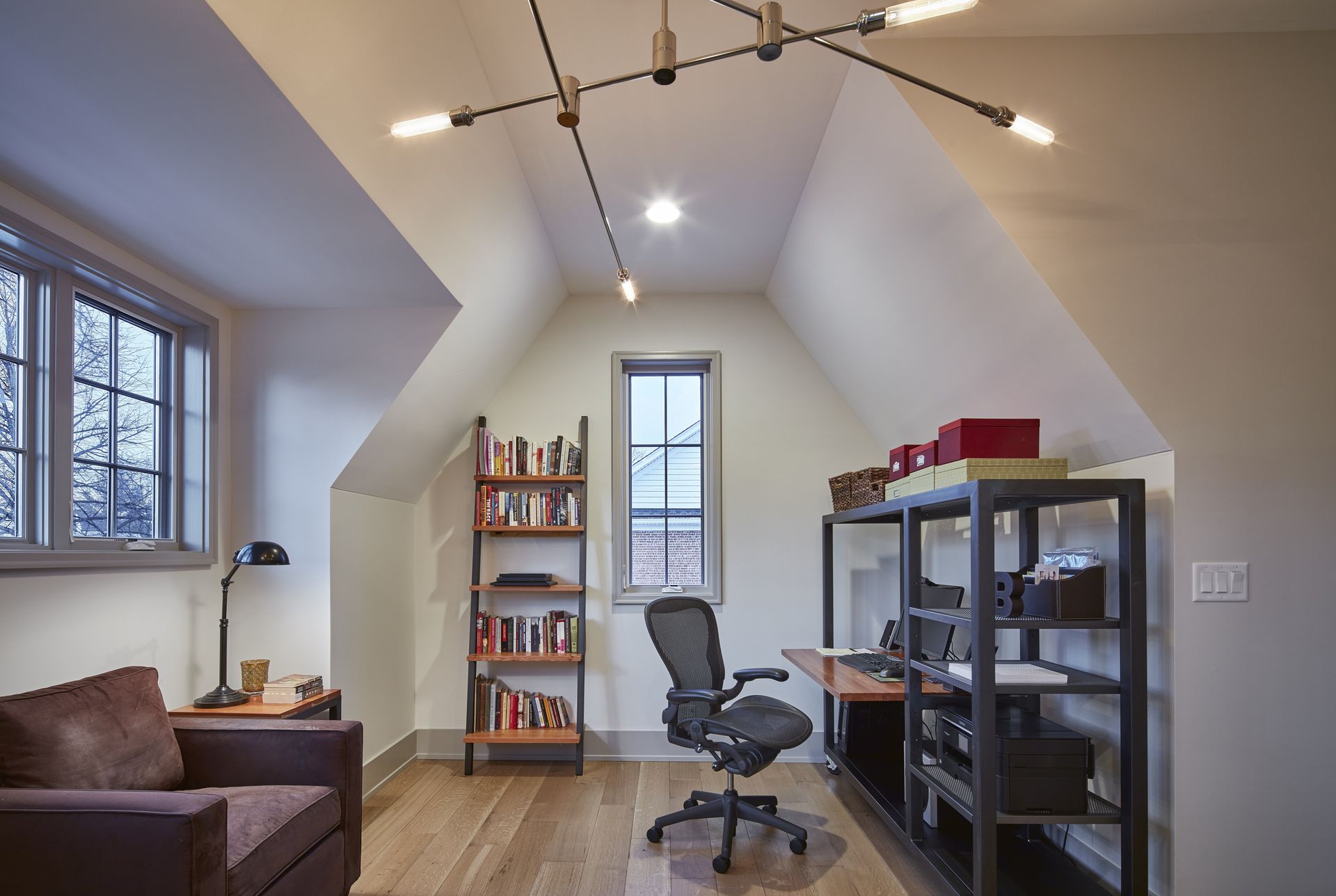 A living room with a chair a desk and a bookshelf