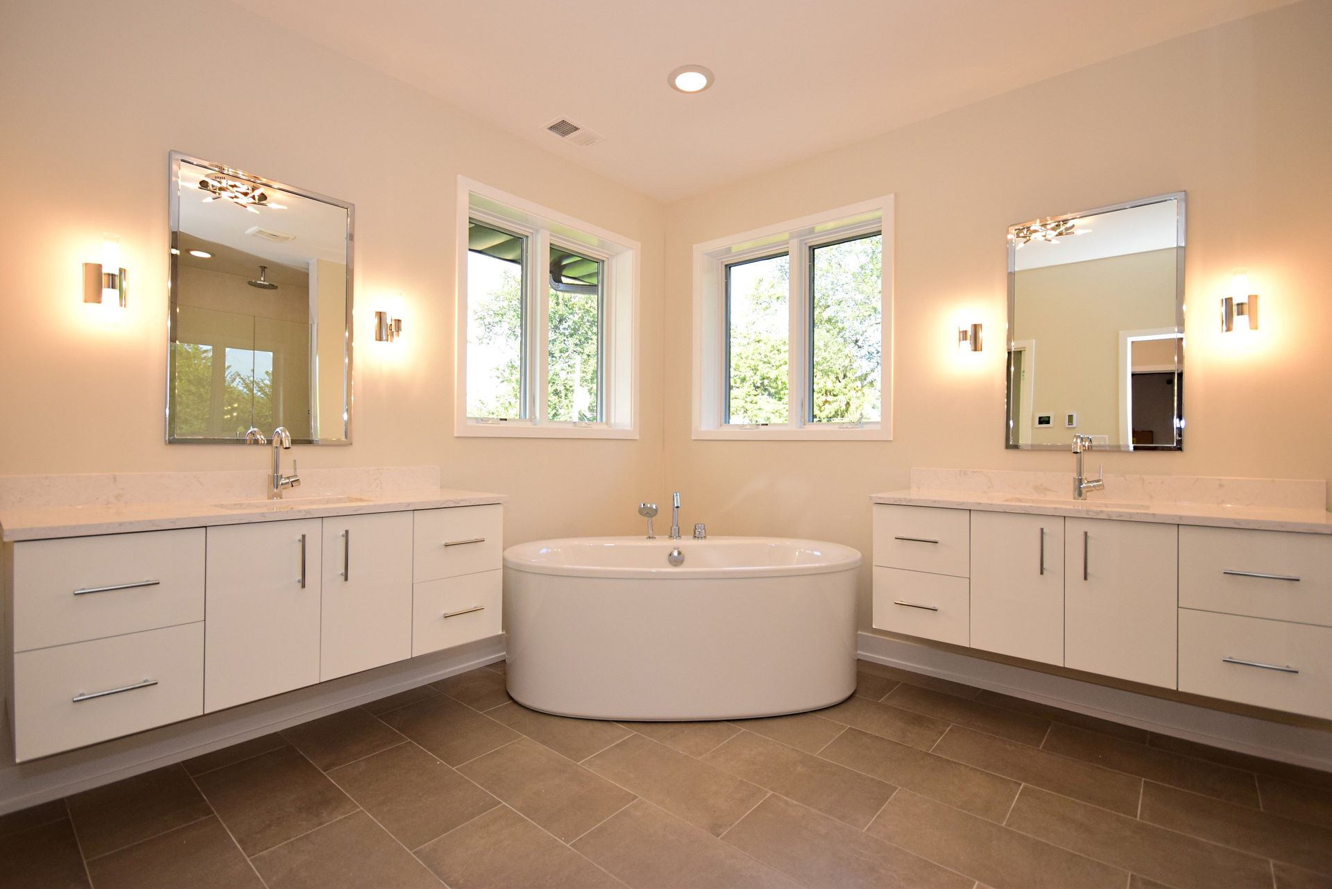 A bathroom with two sinks , a tub and two mirrors.