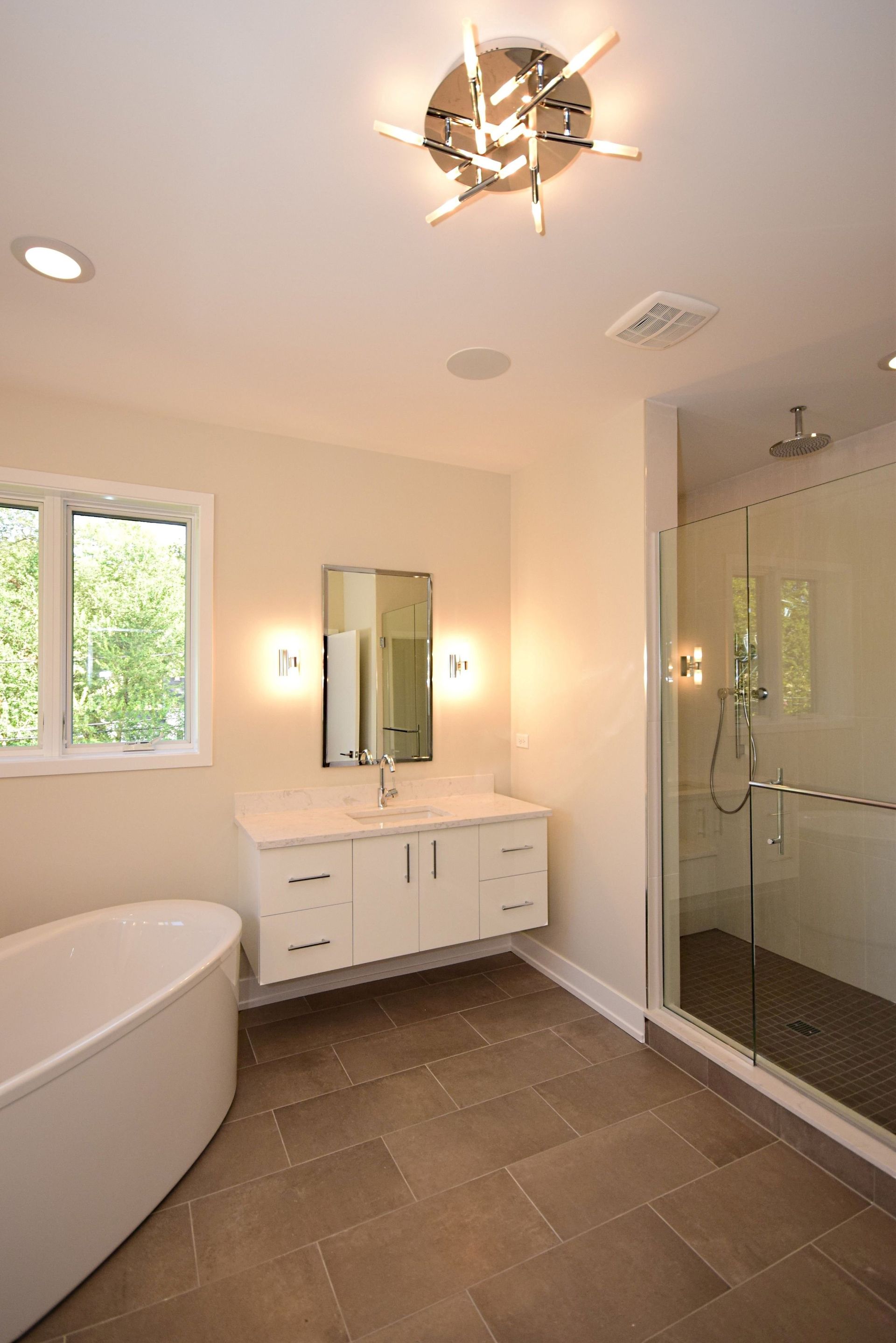 A bathroom with a tub , sink , mirror and shower.