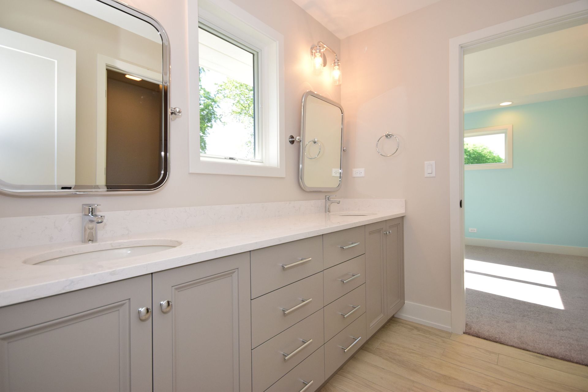 A bathroom with two sinks , a mirror and a window.