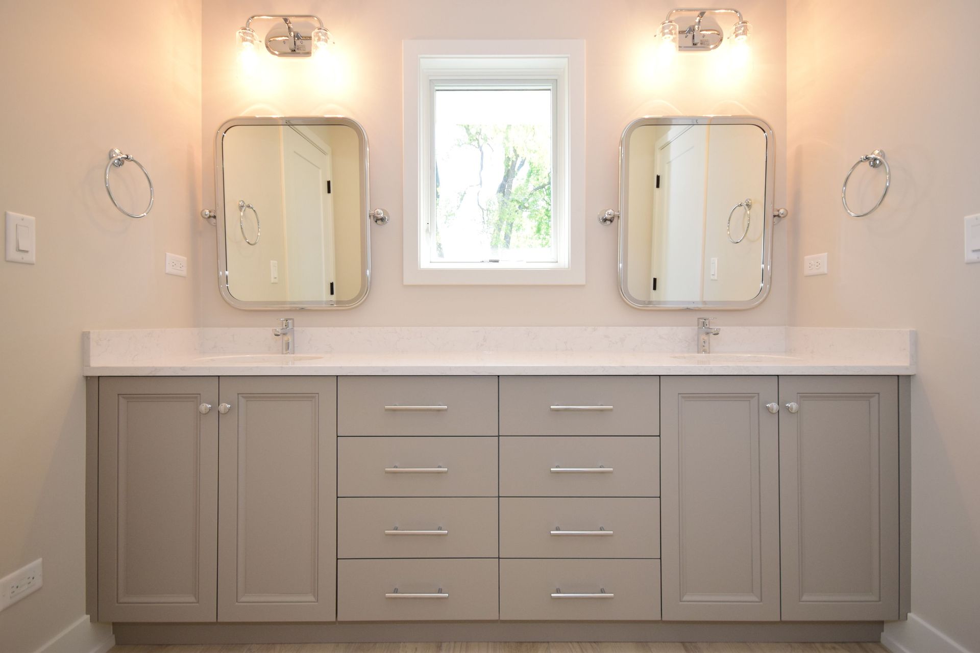 A bathroom with two sinks , two mirrors , and a window.