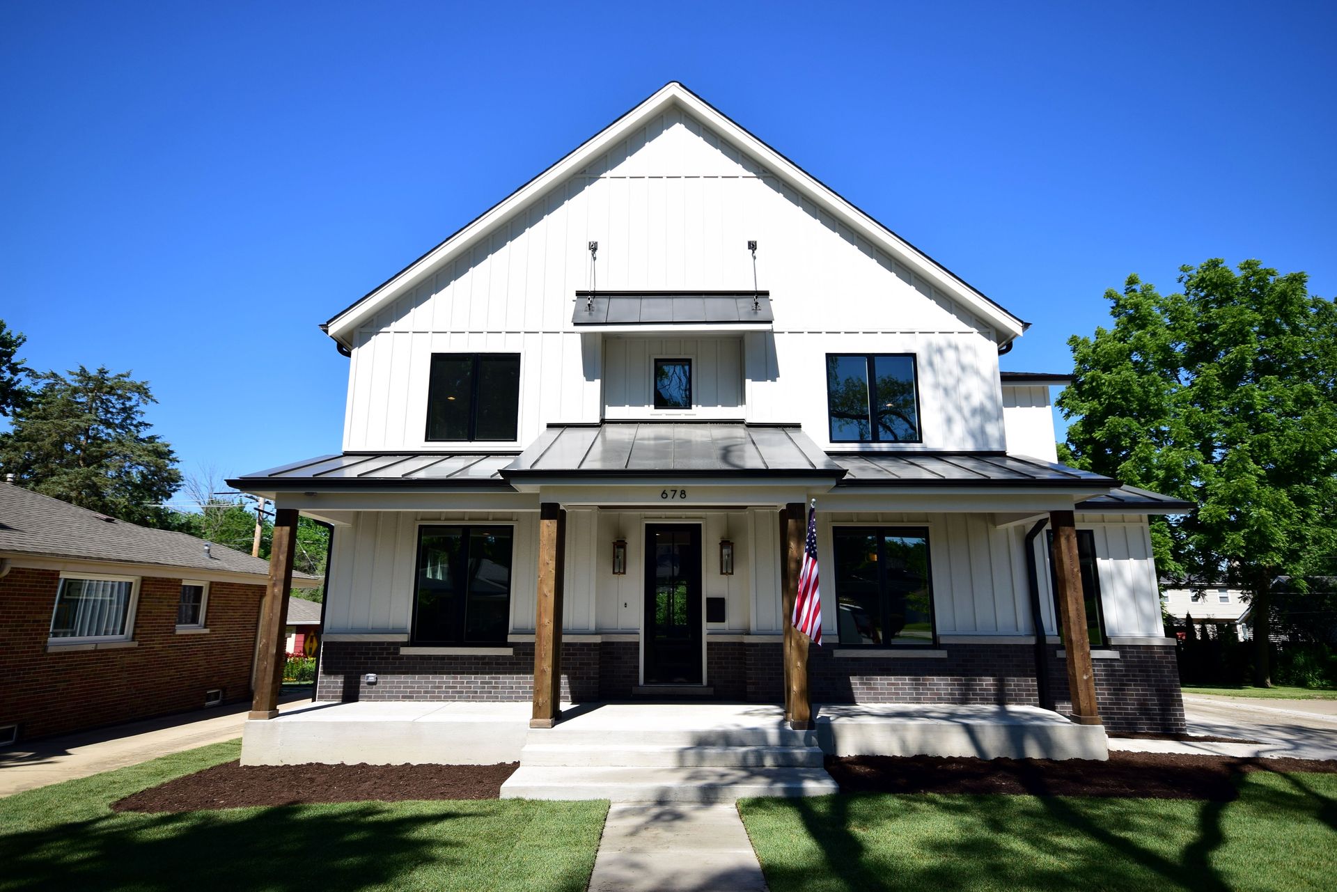 A large white house with a porch and a flag on it
