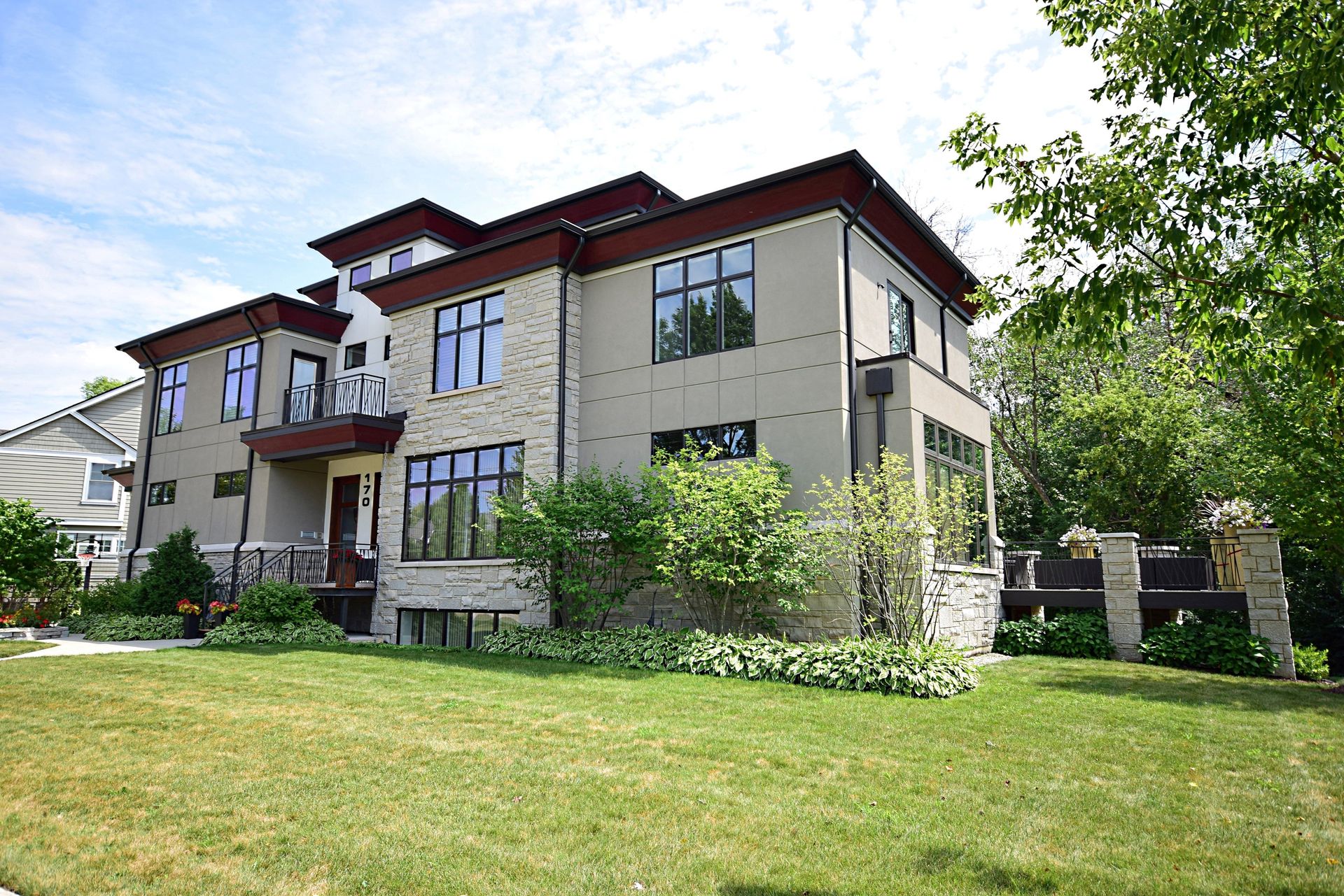 A large house with a lot of windows is sitting on top of a lush green lawn.