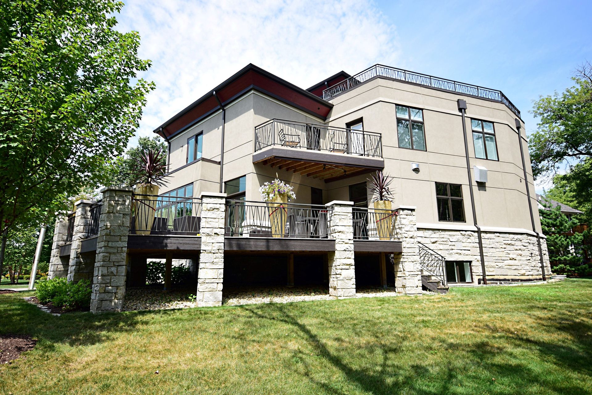 A large house with a balcony is sitting on top of a lush green field.