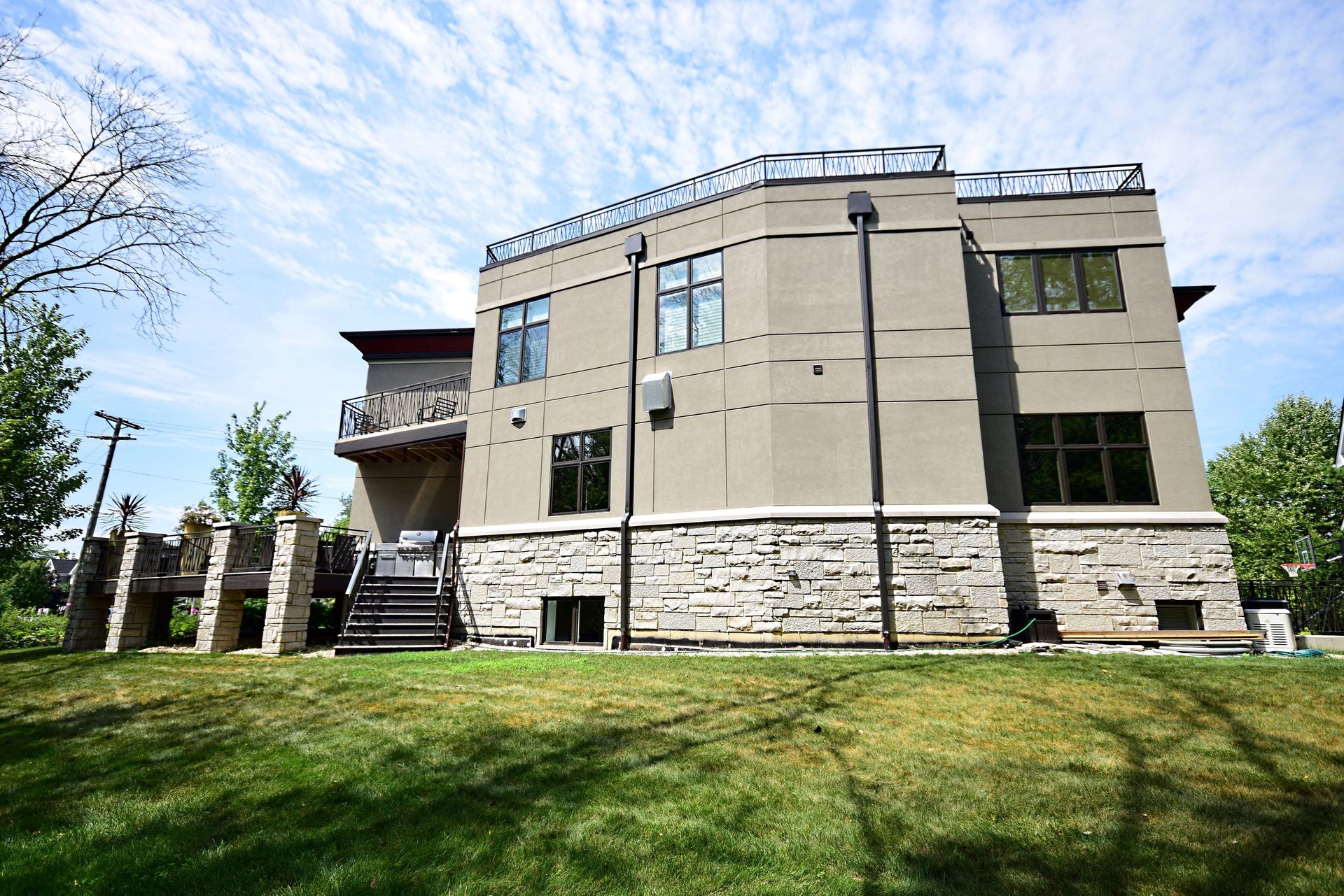 A large house with a lot of windows is sitting on top of a lush green field.