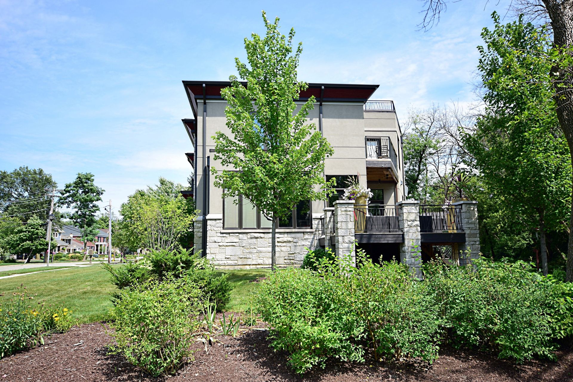 A large house is surrounded by trees and bushes on a sunny day.