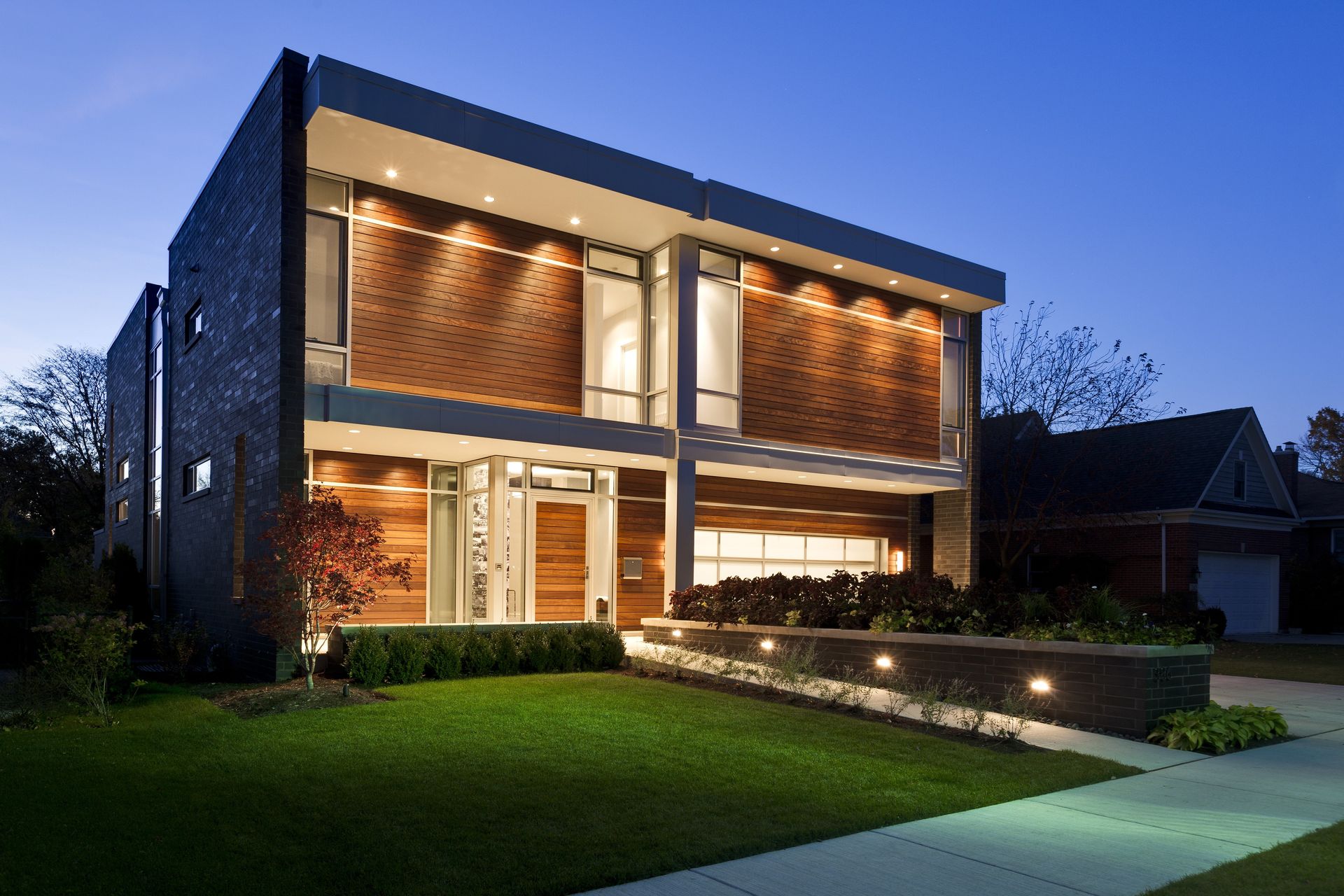 A modern house with a lot of windows is lit up at night