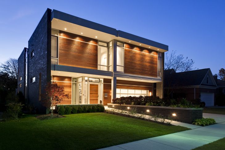 A modern house with a lot of windows is lit up at night