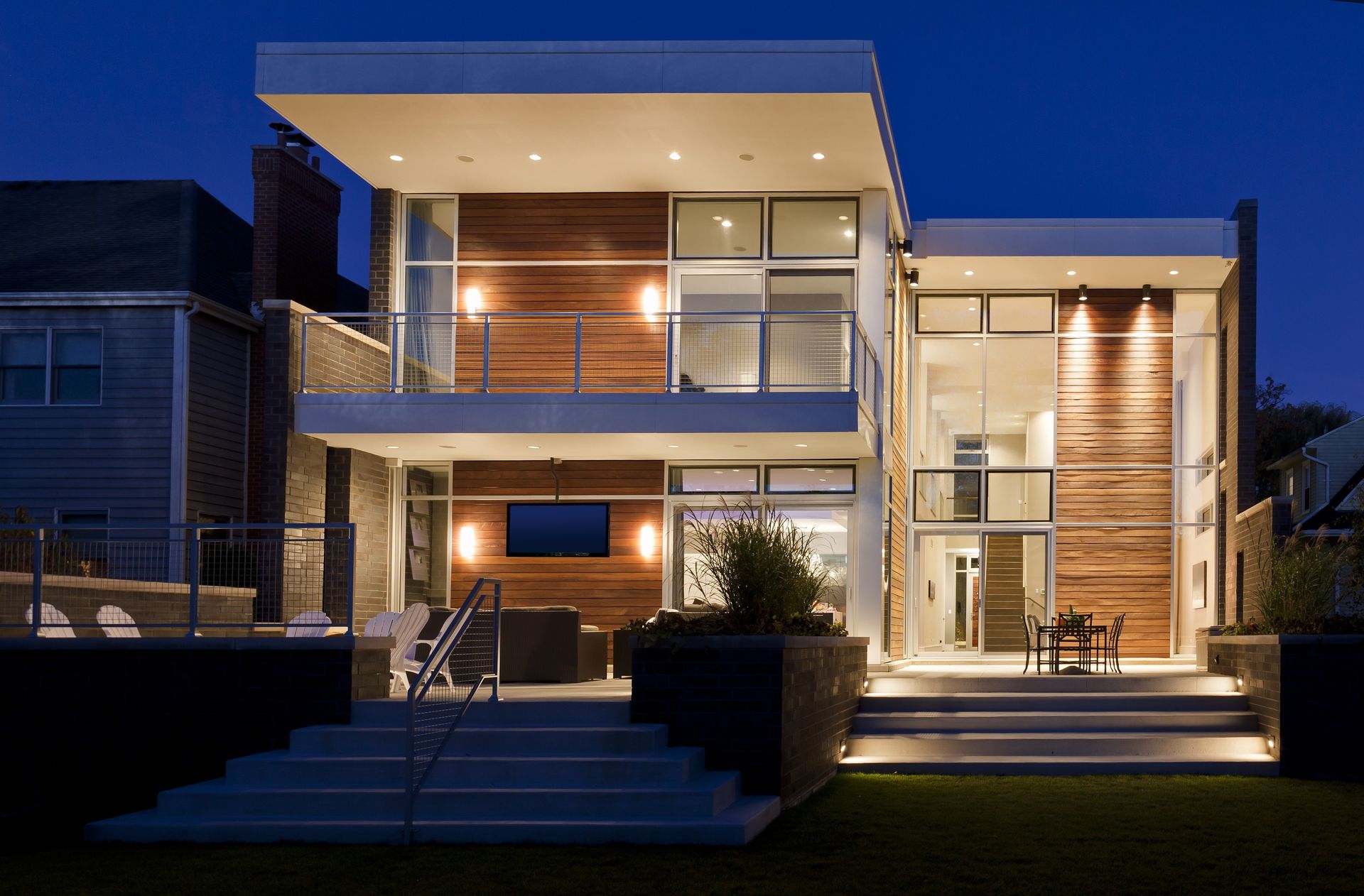 A modern house with a lot of windows is lit up at night