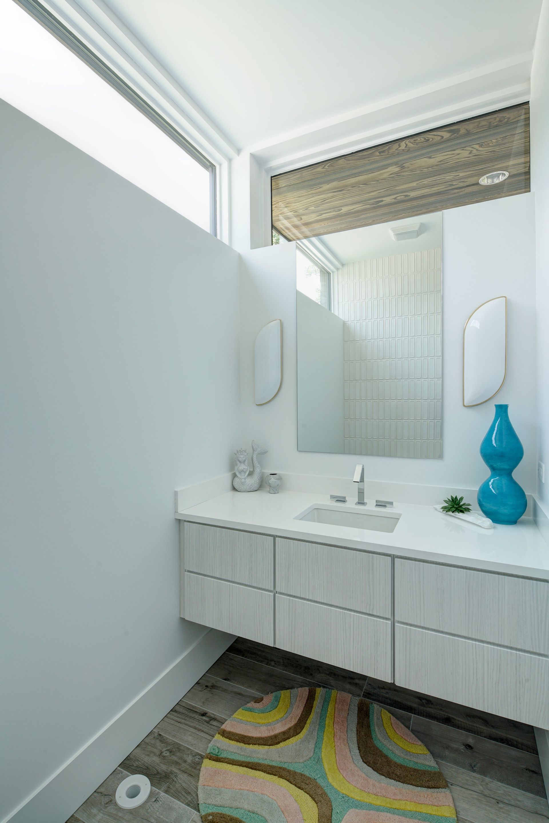 A bathroom with a sink , mirror , and rug.