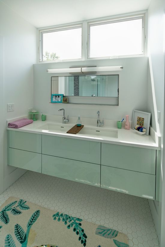 A bathroom with two sinks , a mirror and a rug.