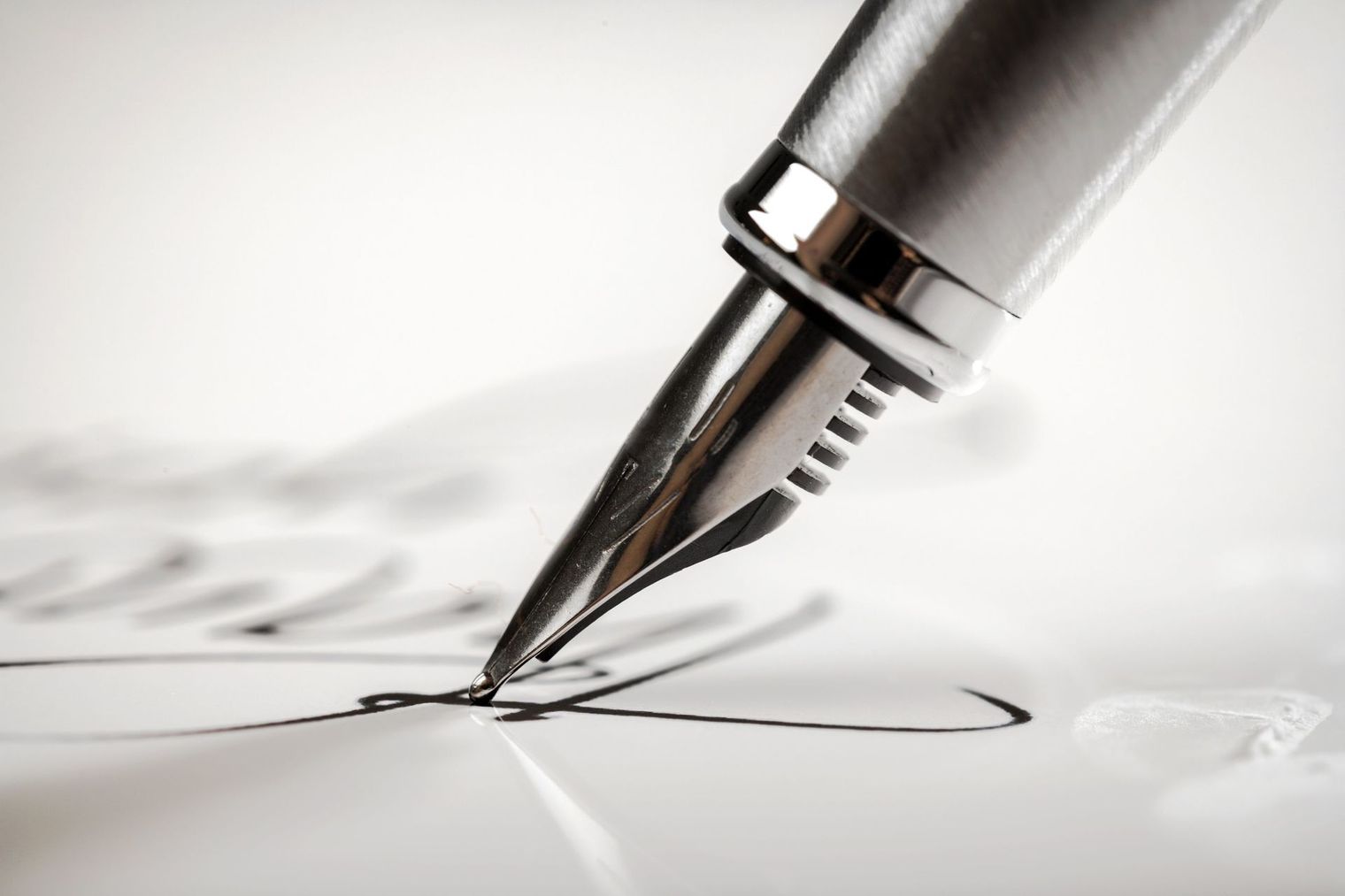 A fountain pen is writing on a piece of paper