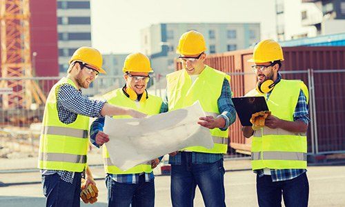 Group of smiling builders seeing blueprint Group of smiling builders seeing blueprint