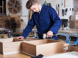 Worker Chiseling Plank at Workshop — Beaumont, CA — Absolute Cabinets Inc Worker Chiseling Plank at Workshop — Beaumont, CA — Absolute Cabinets Inc