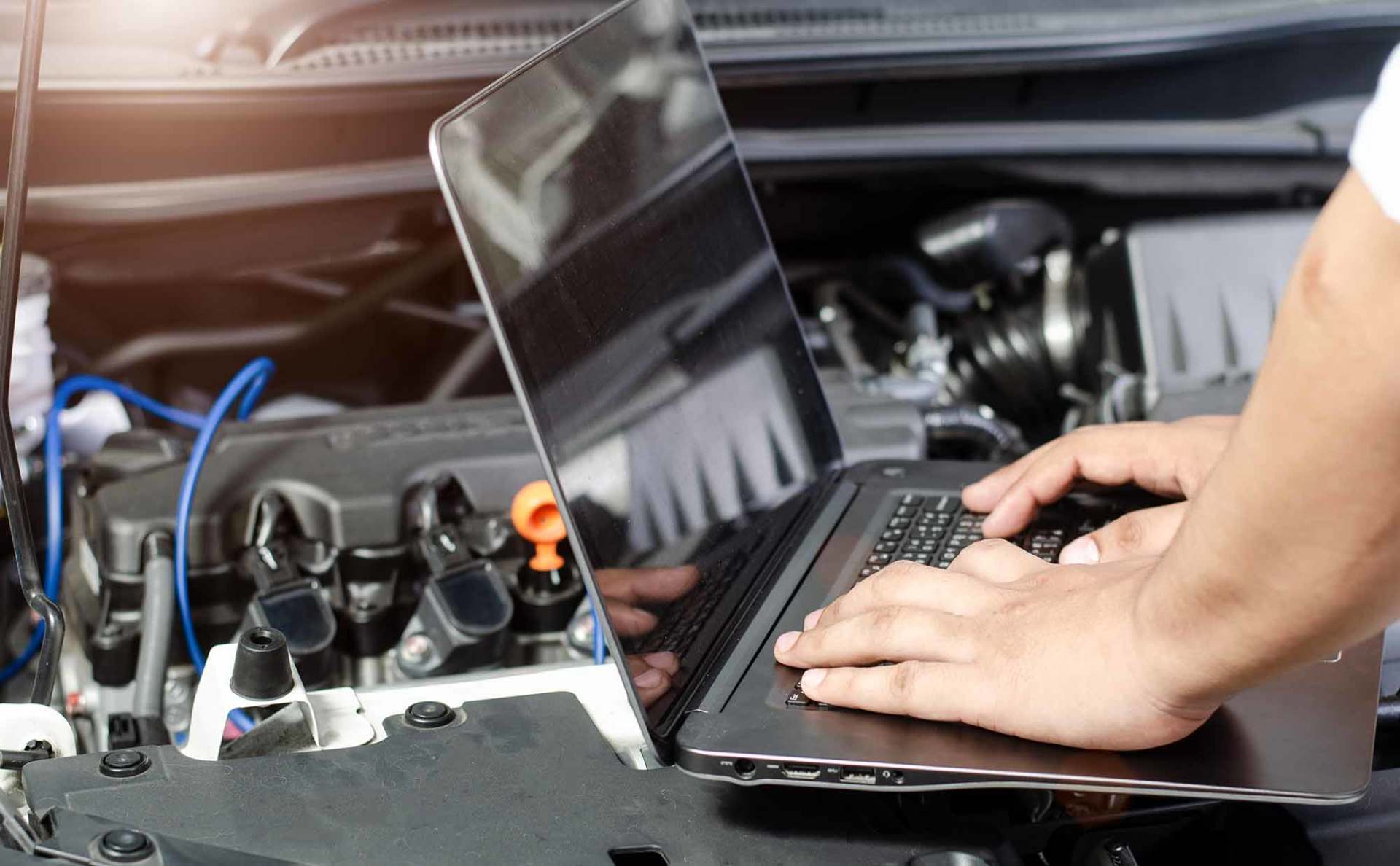 Detail of a mechanic using electronic diagnostic equipment to tune a car