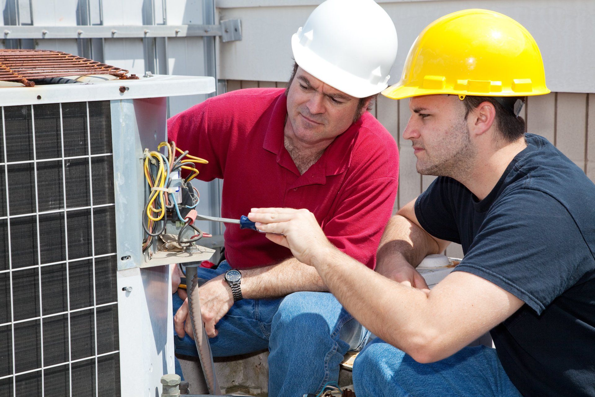 2 hvac repair technicians inspecting ac unit