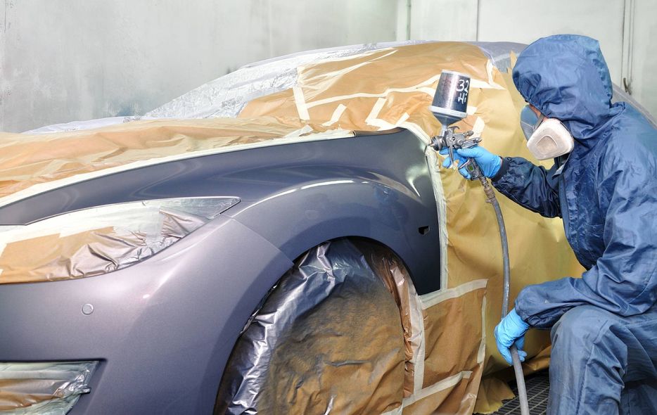 meccanico impegnato nella verniciatura di una autovettura