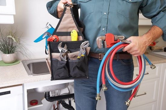 Plumber with plumbing tools on the kitchen