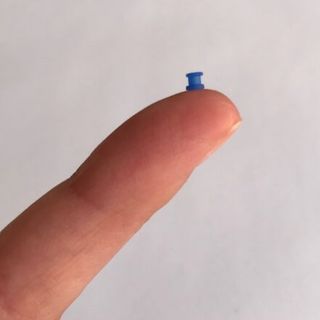O dreno de ouvido é uma pequena estrutura cilíndrica de silicone que é inserida no tímpano. Tubo de ventilação ou dreno de ouvido sobre o dedo de um adulto