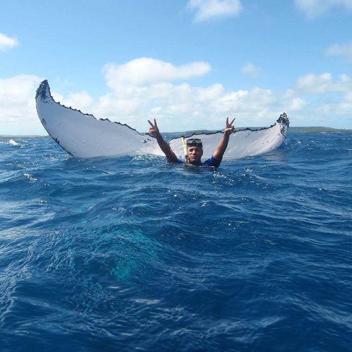 Tour guide throwing up the peace sign in front of a sailing whale