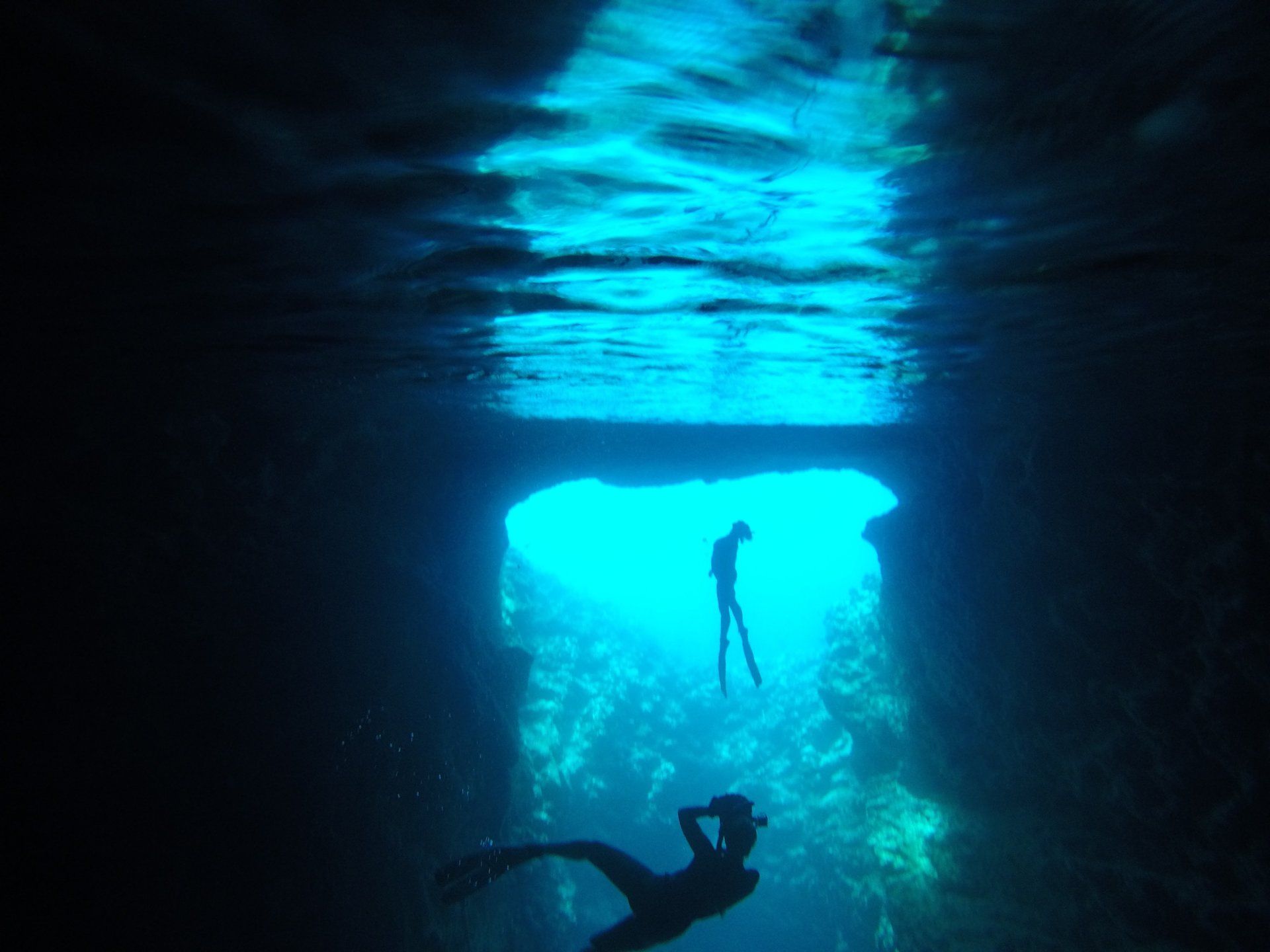 Silhouette of a freediver and photographer in an underwater cave