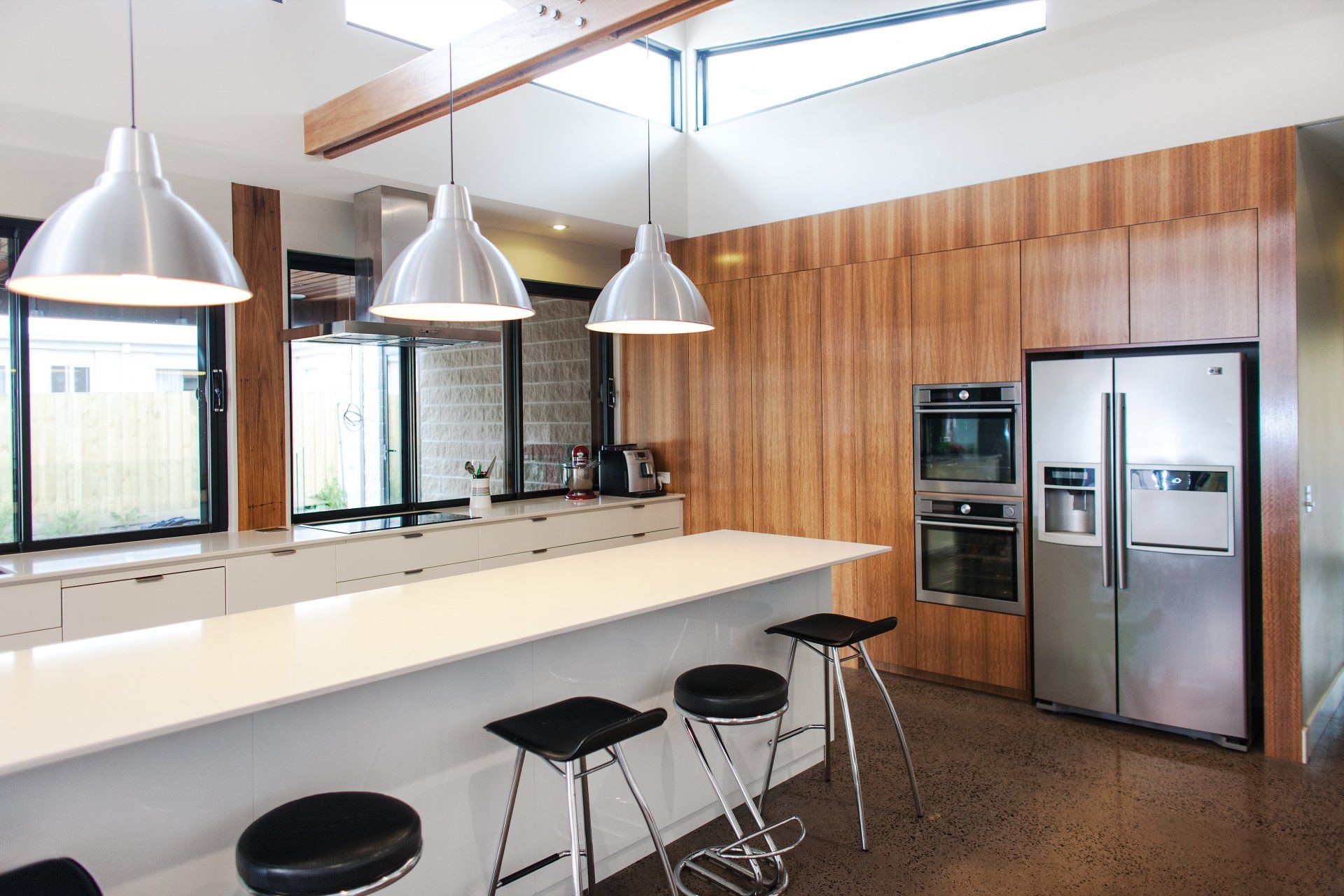 A kitchen with stools , a refrigerator , and a large island.