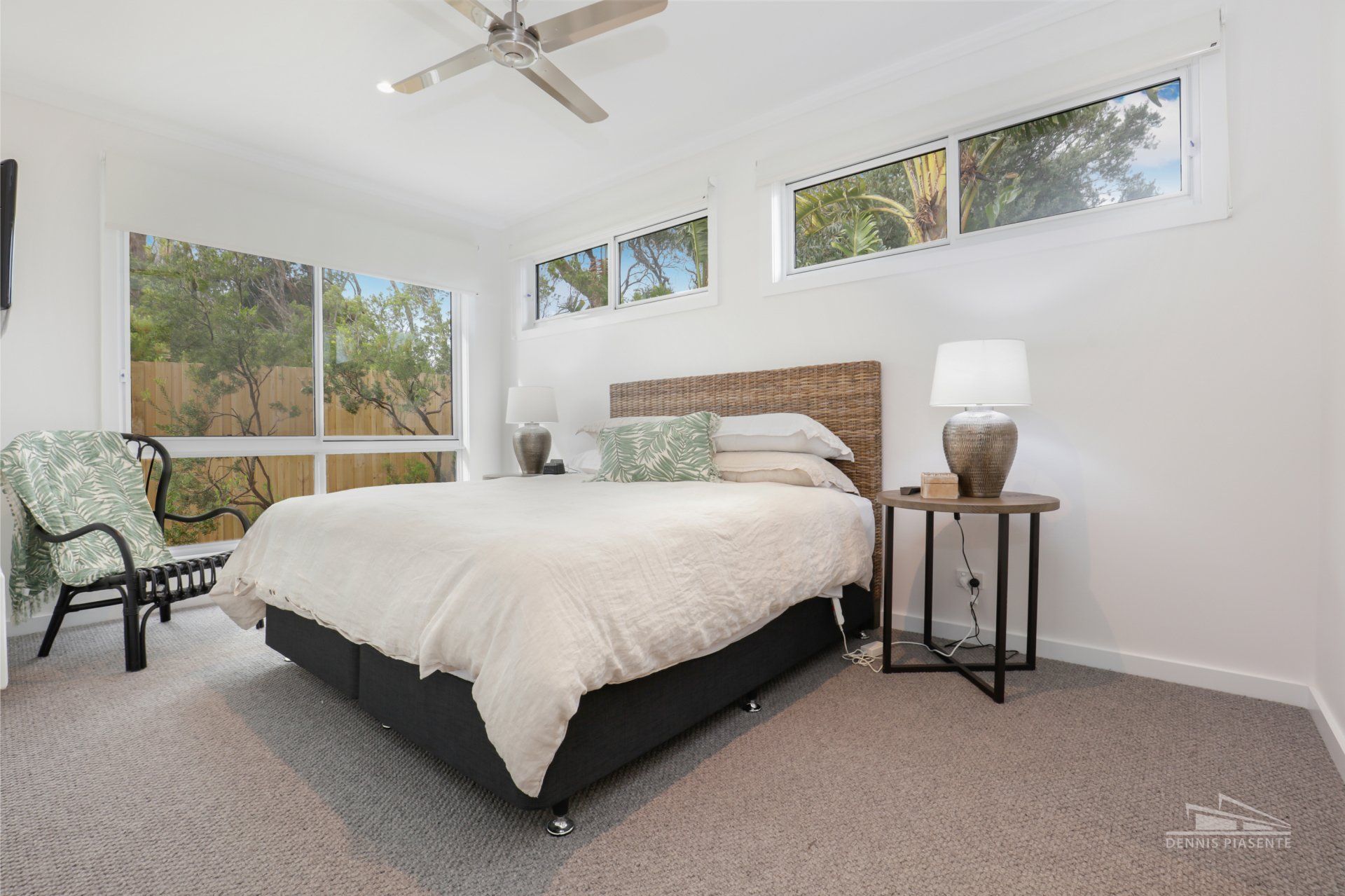A bedroom with a king size bed and a ceiling fan.
