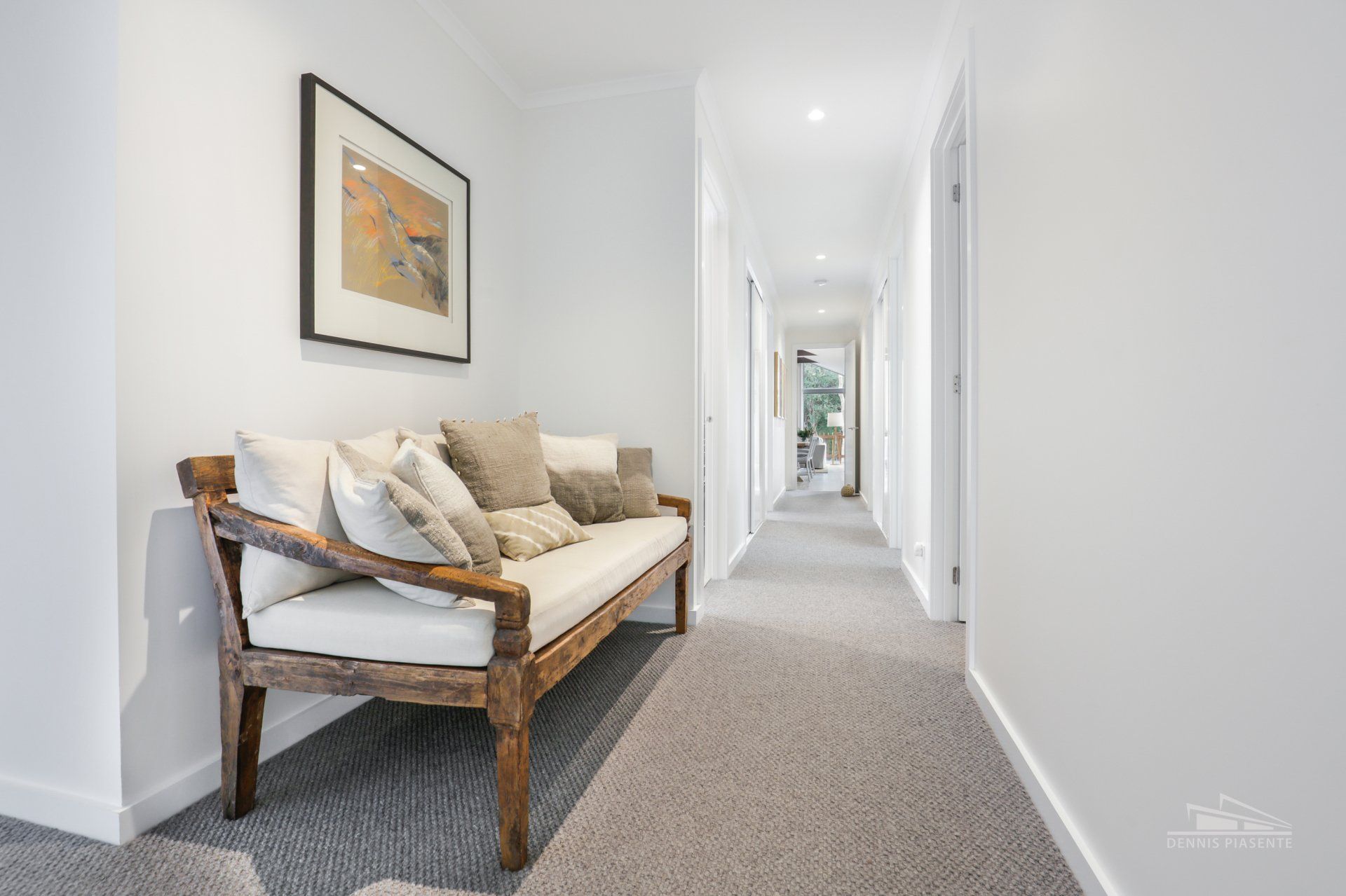A long hallway with a couch and a picture on the wall.