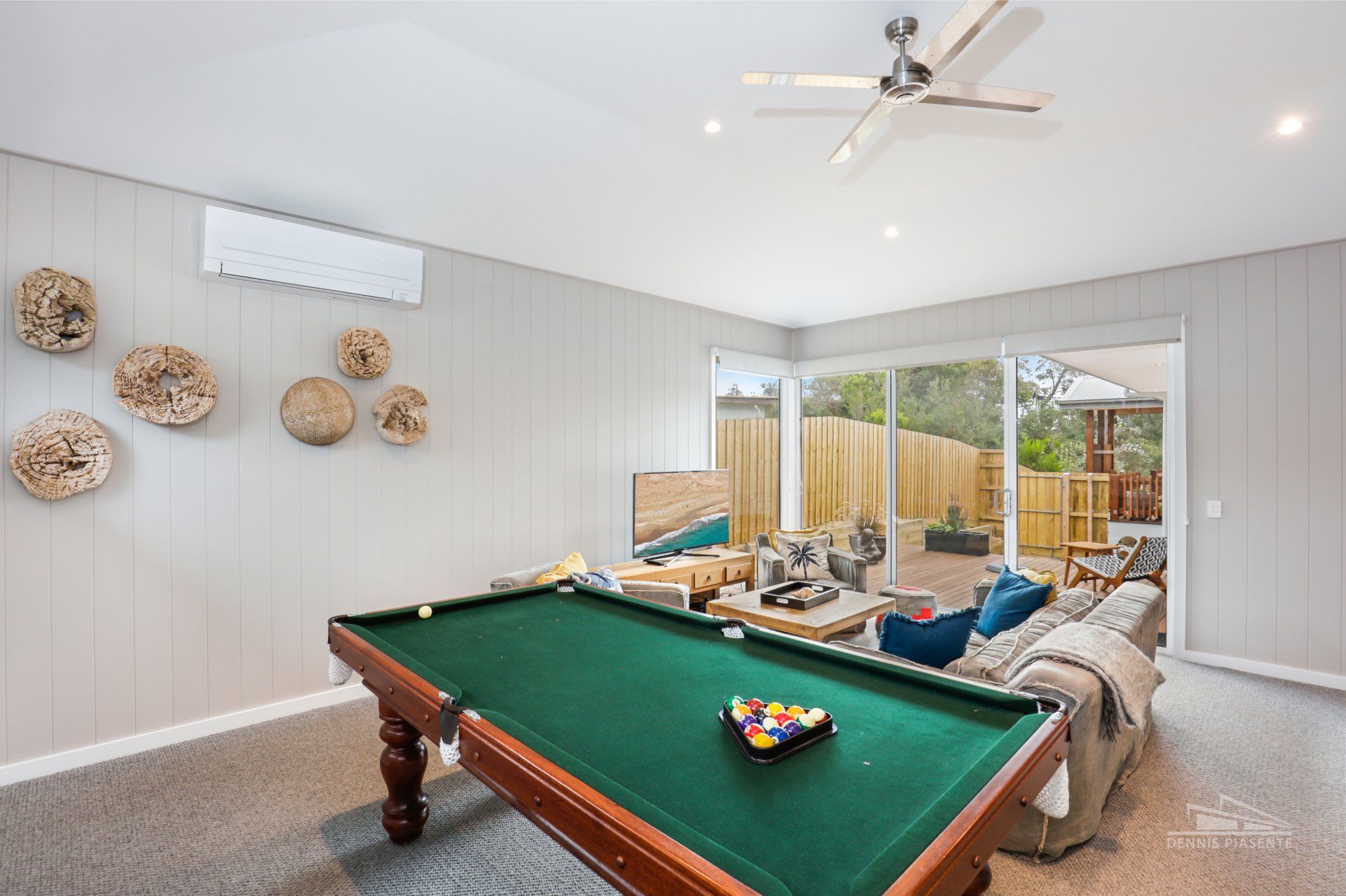 A pool table in a living room with a ceiling fan.