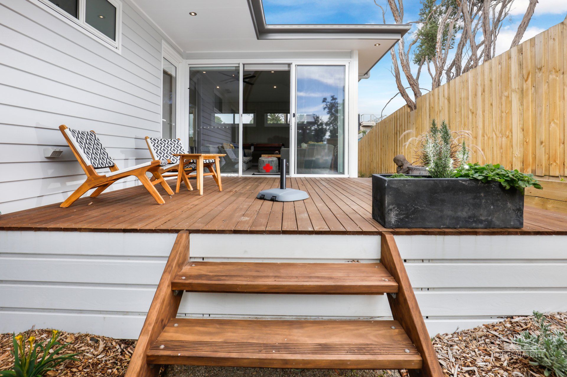 A wooden deck with stairs leading up to it next to a house.