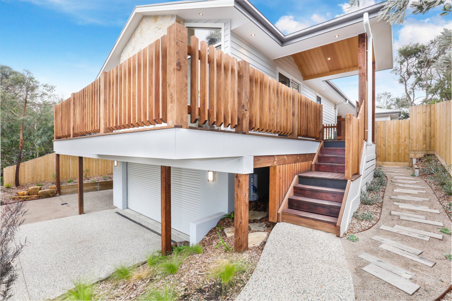 A white house with a wooden deck and stairs