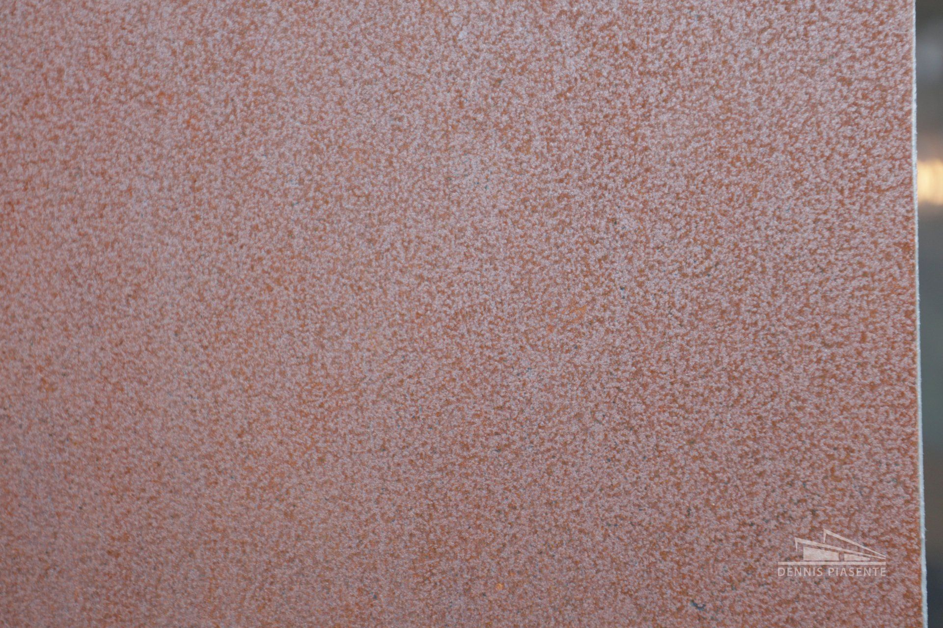 A close up of a red tile with a stainless steel border