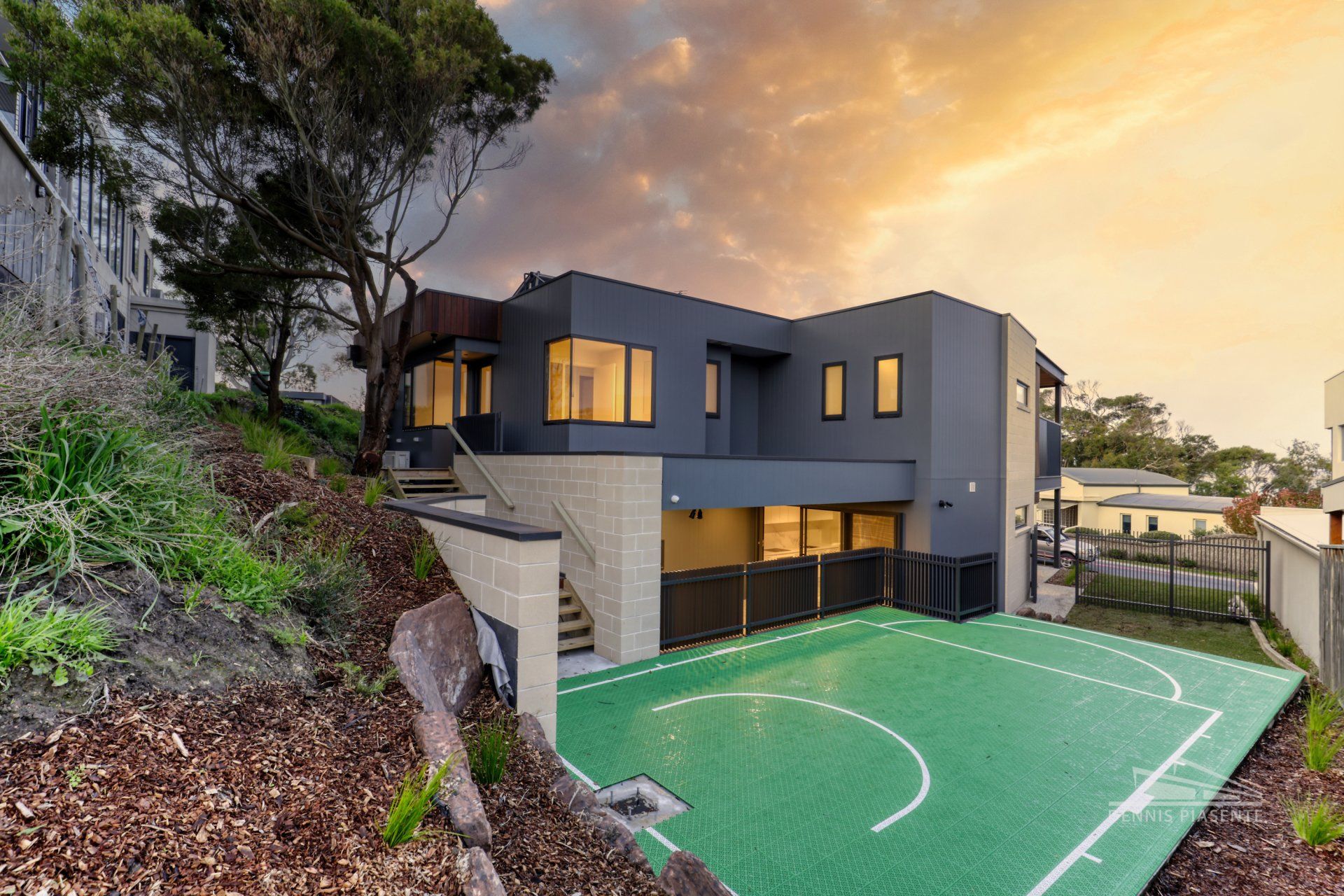 A large house with a basketball court in front of it.