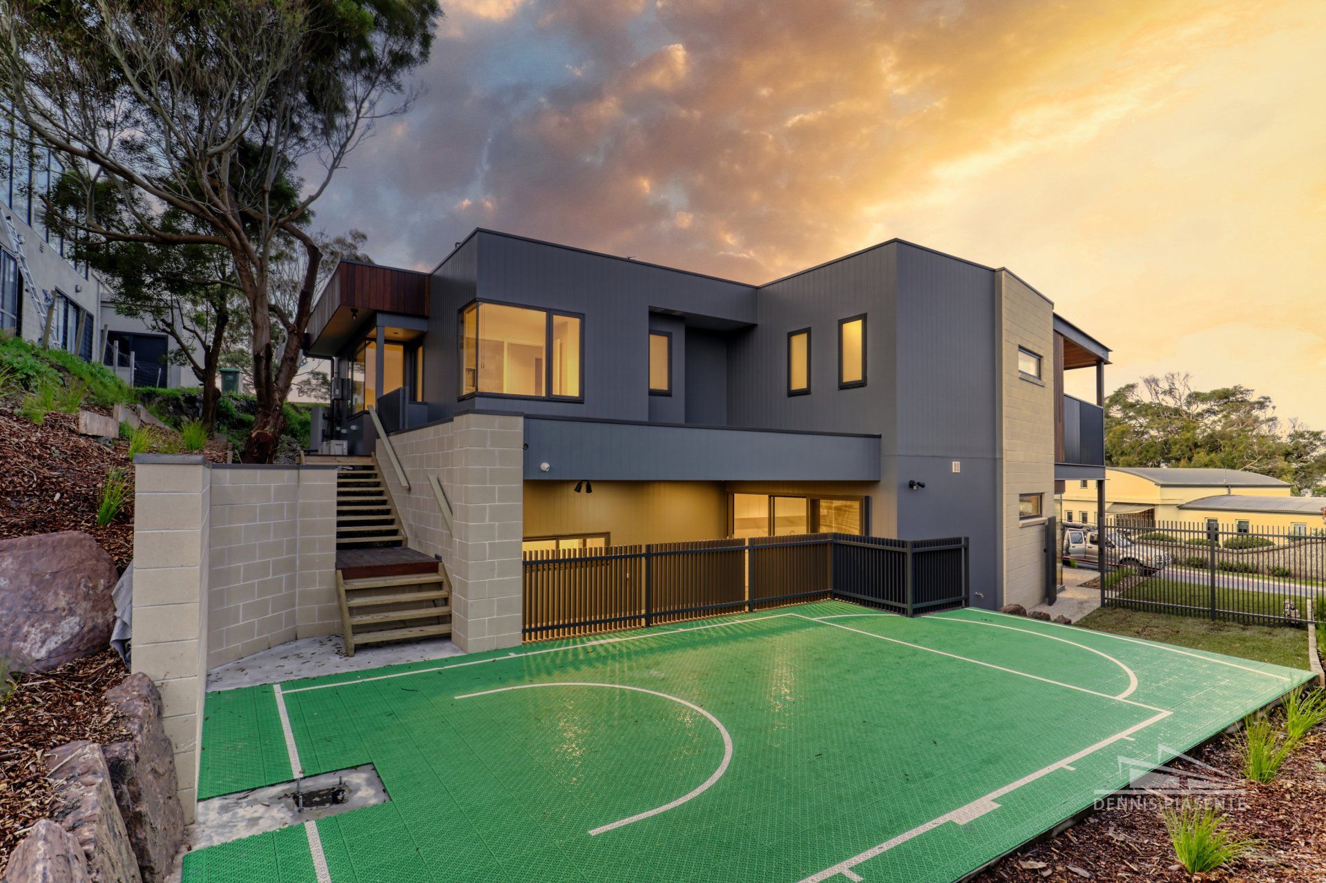 A large house with a basketball court in front of it.