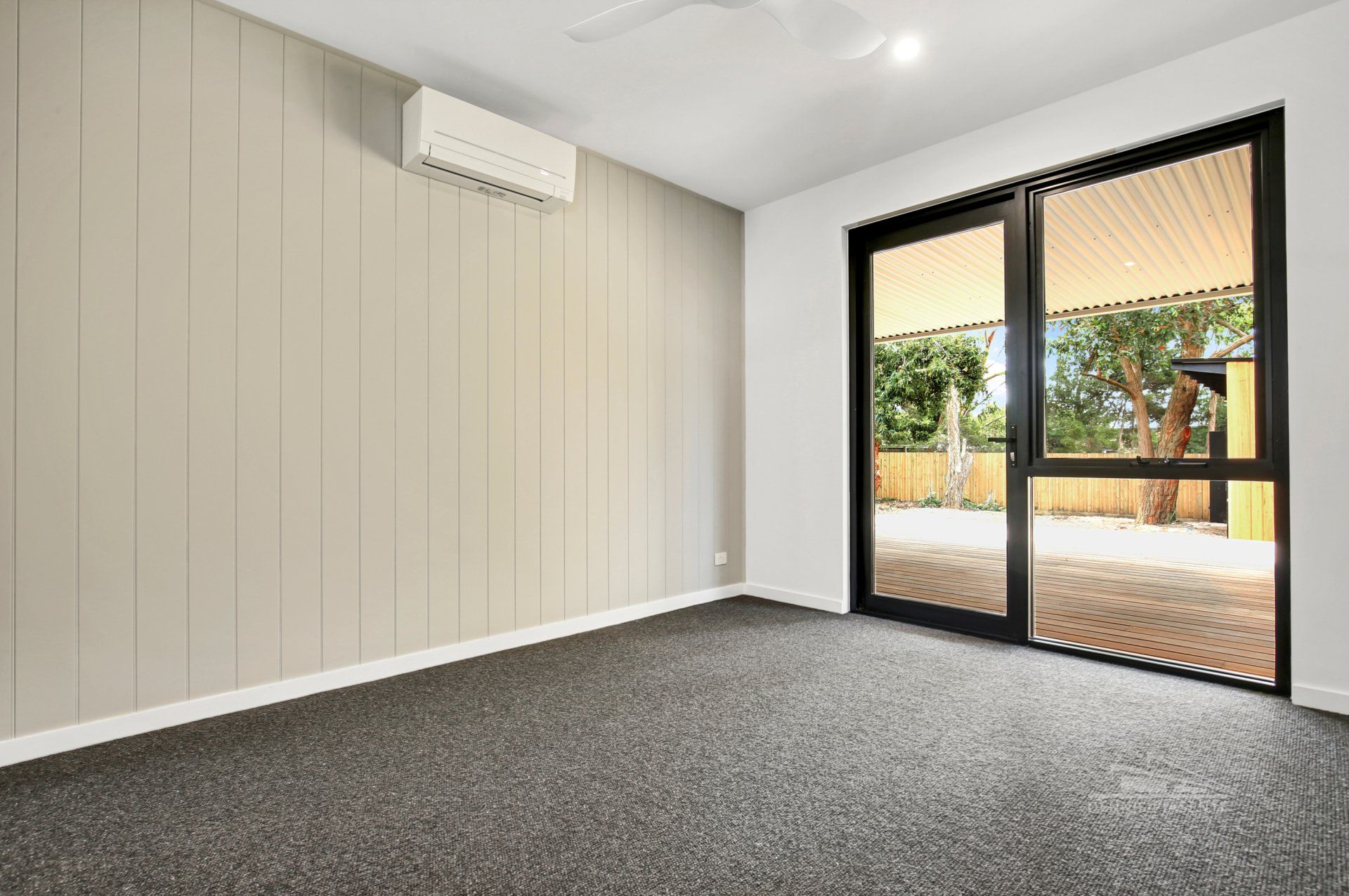 An empty room with a sliding glass door and a ceiling fan.