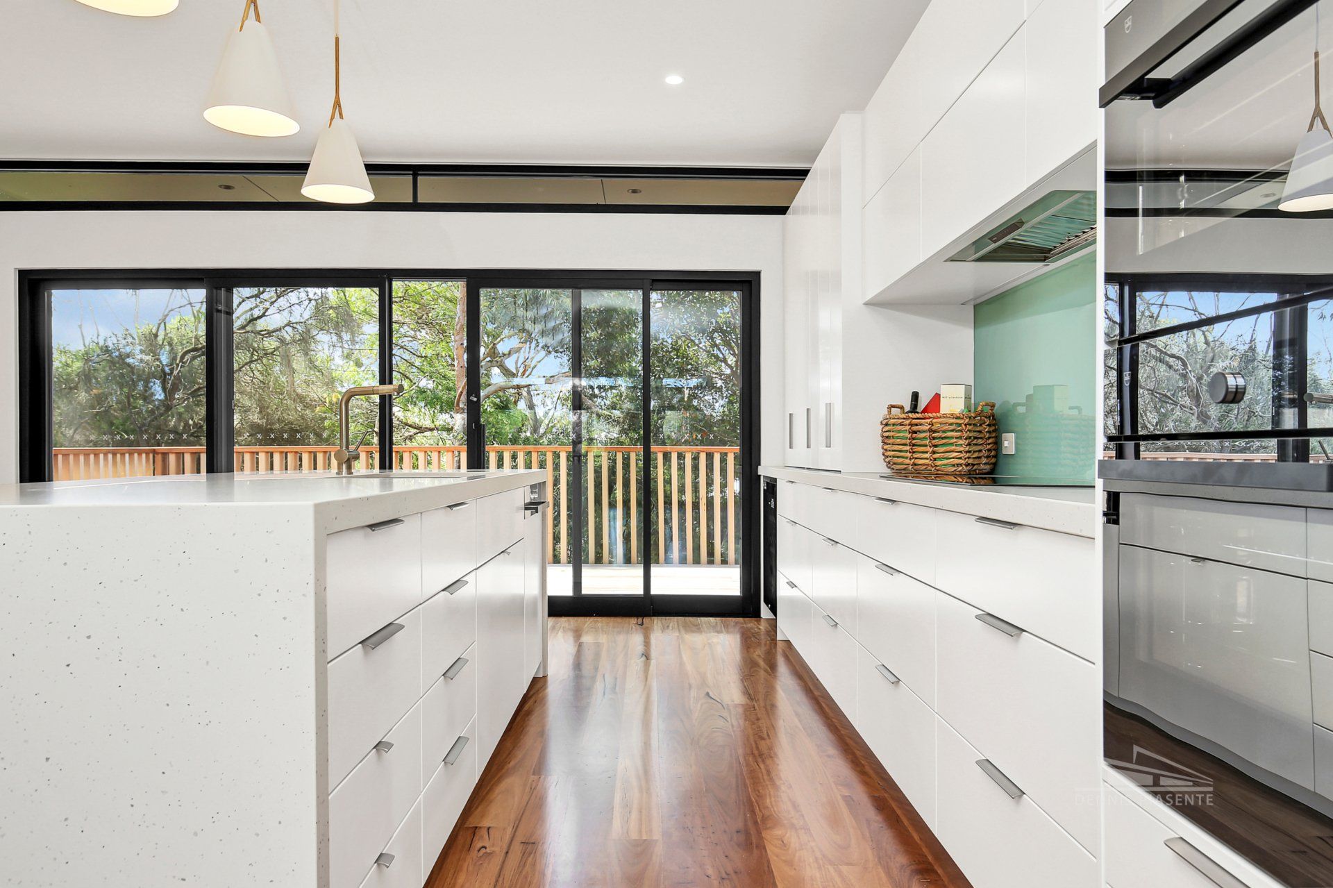 A kitchen with white cabinets and hardwood floors and a large island.
