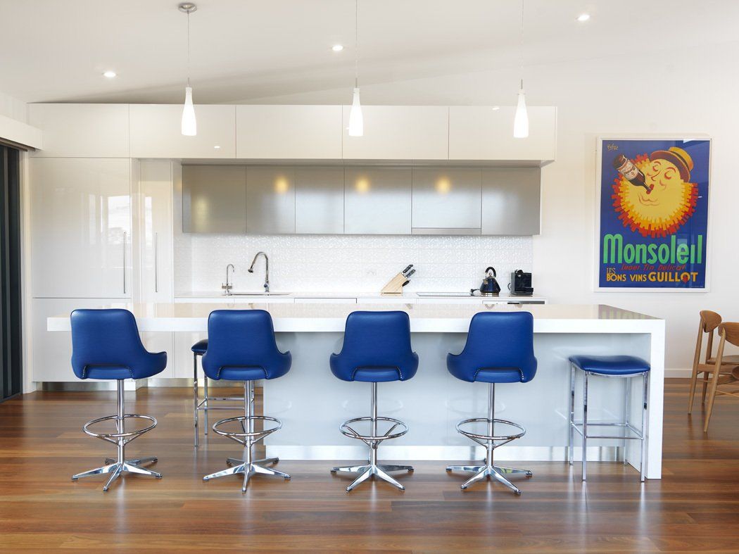 A kitchen with blue chairs and a poster on the wall that says monselle
