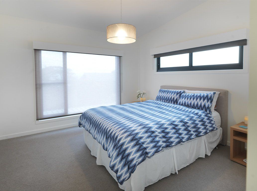 A bedroom with a large bed and two windows