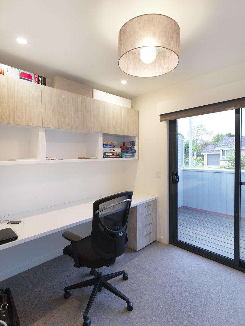A room with a desk and chair and a sliding glass door.